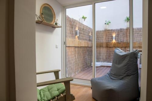 een woonkamer met een stoel en een glazen schuifdeur bij Charming 1 Bedroom Apartment w/ Terrace Near Belém in Lissabon