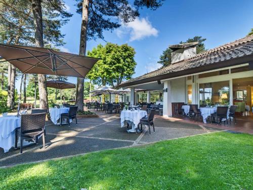 an outdoor patio with tables and chairs and an umbrella at Golf Hotel La Pinetina in Appiano Gentile