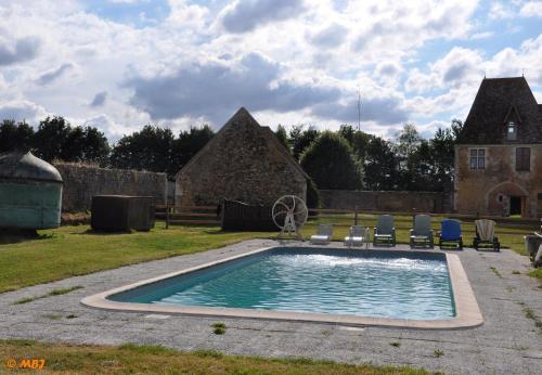 a swimming pool in a yard with chairs and a house at Manoir du Bois Joly - Roulotte Gitane in Margon