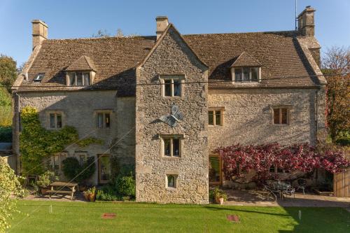an old stone house with a clock on it at The Barracks in Northleach