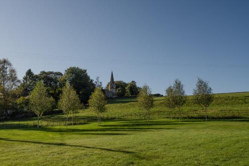 a field with trees and a church in the distance at The Barracks in Northleach