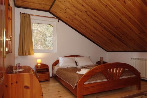 a bedroom with a wooden bed and a window at Семеен хотел Орфей in Teshel