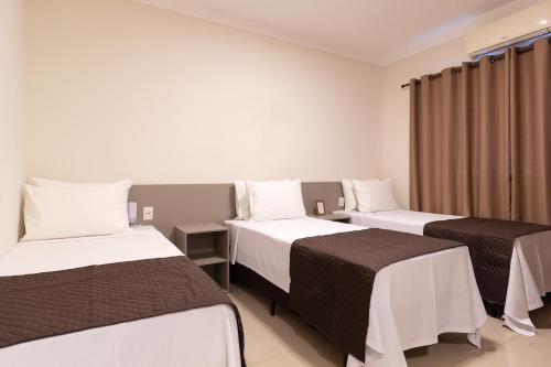 a hotel room with two beds and a window at VILLA NOMAD HOTEL in Uberaba