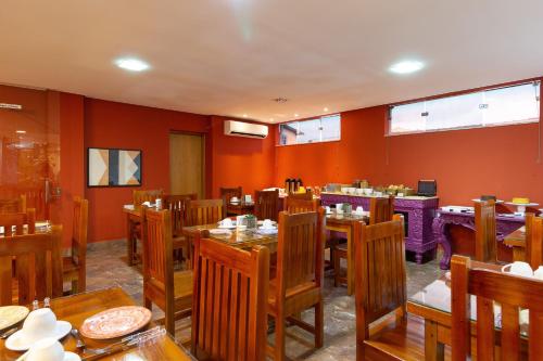 a restaurant with orange walls and wooden tables and chairs at VILLA NOMAD HOTEL in Uberaba