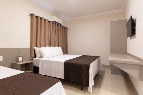 a hotel room with two beds and a flat screen tv at VILLA NOMAD HOTEL in Uberaba
