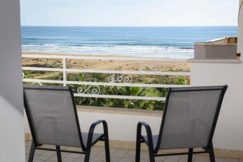 2 sillas sentadas en un balcón con vistas a la playa en MADAGÌ Beachfront Apartments, en Pozzallo