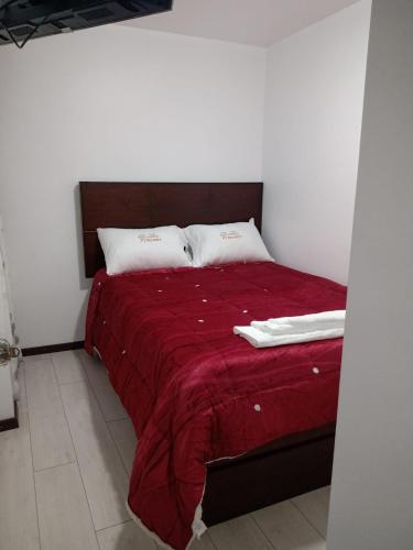 1 cama con manta roja y 2 almohadas en PYMABET, en Huancavelica