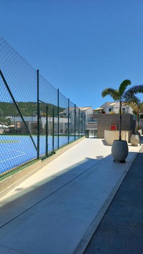a fence with a palm tree next to a body of water at apartamento de frente para o mar com linda area de lazer in Arraial do Cabo