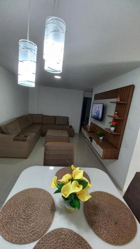 a living room with a table with yellow flowers on it at apartamento de frente para o mar com linda area de lazer in Arraial do Cabo
