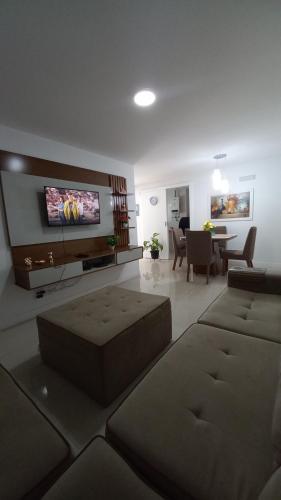 a living room with two ottomans and a tv on the wall at apartamento de frente para o mar com linda area de lazer in Arraial do Cabo