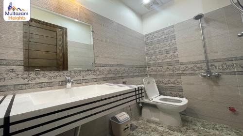 a bathroom with a sink and a toilet and a mirror at Multazam Heights, DHA Phase 8 - 3 Bedrooms Luxury Apartments in Lahore