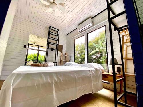 a bedroom with a large white bed and windows at Hoja Azul Loft Guanacaste in Hojancha