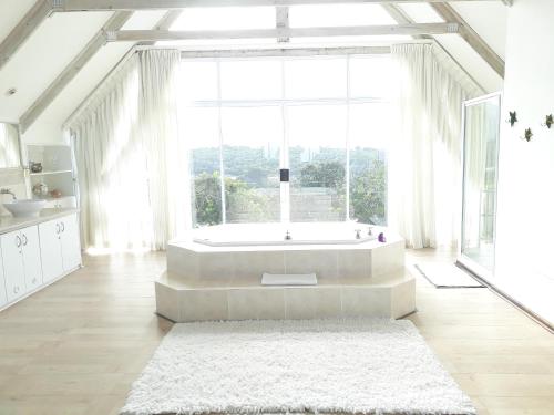 a large white bathroom with a tub and a large window at Whales Way Ocean Retreat in Wilderness