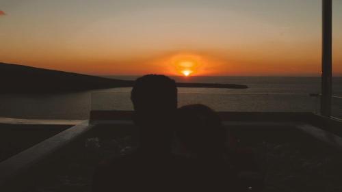 a person sitting in a bath tub watching the sunset at Marizan Caves & Villas in Oia