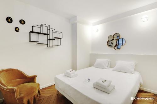 um quarto branco com uma cama e uma cadeira em CMG Pyrénée-Porte de Montreuil - G em Paris