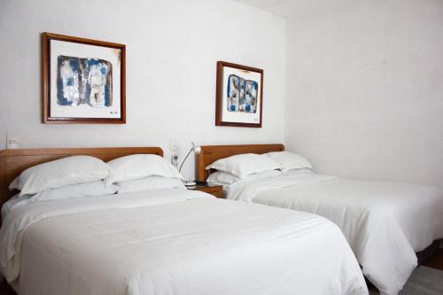 two beds in a hotel room with white sheets at Finca del Rocio in Parras de la Fuente
