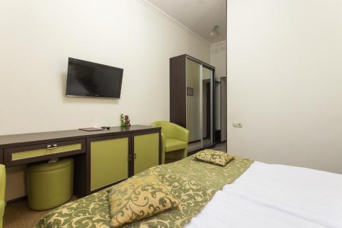 a bedroom with a bed and a desk and a tv at Hotel Voyage in Kharkiv