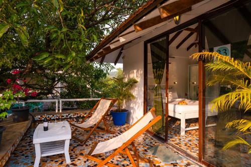 a patio with two chairs and a table and a bed at Moustache Goa Luxuria in Vagator