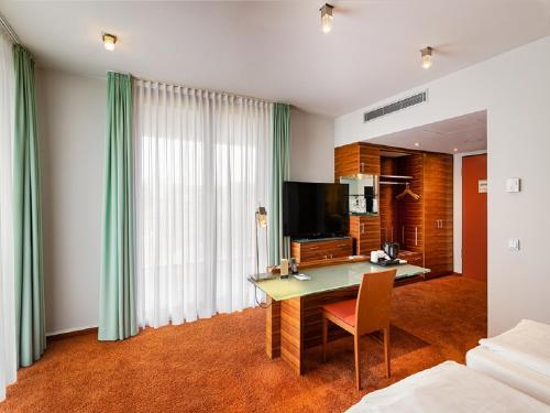 a room with a desk with a television and a bed at Schlosshotel Hellenstein in Heidenheim