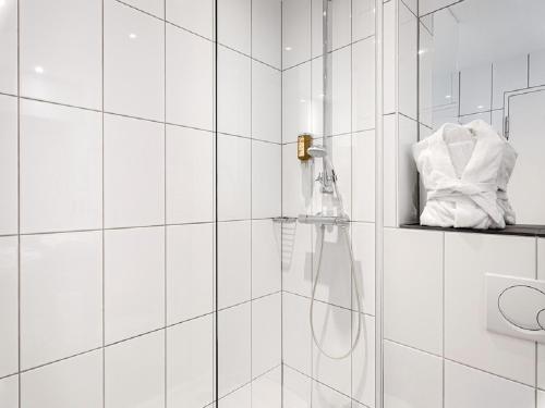 a white tiled bathroom with a shower with a hose at Schlosshotel Hellenstein in Heidenheim