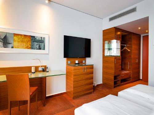 a hotel room with a desk and a tv at Schlosshotel Hellenstein in Heidenheim