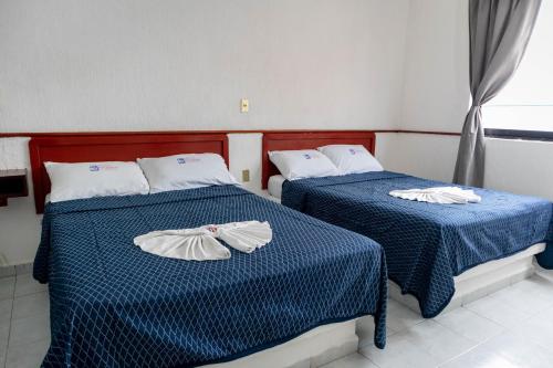 - 2 lits dans une chambre avec des draps bleus et blancs dans l'établissement Hotel Madero, à Villahermosa