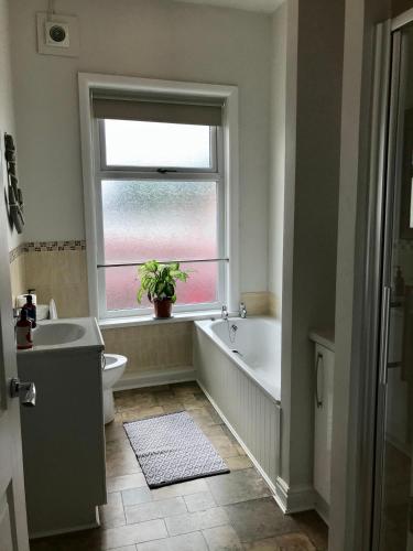 a bathroom with a tub and a sink and a window at 3 Bedroom House Close to M6 & M55 in Preston