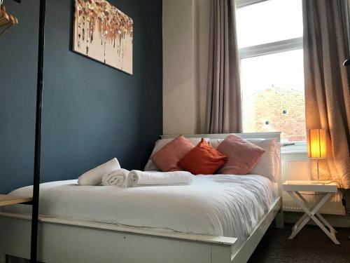 ein Schlafzimmer mit einem Bett mit Kissen und einem Fenster in der Unterkunft 3 bedroom house in Preston close to M6 & M55 in Preston