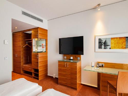a room with a bed and a desk and a tv at Schlosshotel Hellenstein in Heidenheim
