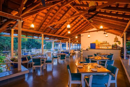 a restaurant with wooden ceilings and tables and chairs at Moustache Goa Luxuria in Vagator