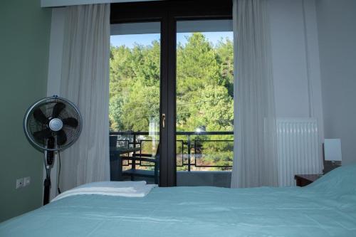 a bedroom with a bed and a window with a fan at Οροφομεζονέτα σε συγκρότημα κατοικιών-Μοναδική θέα in Poligiros