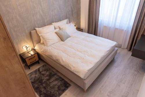 un letto con lenzuola e cuscini bianchi in una camera da letto di Apart B&V a Braşov