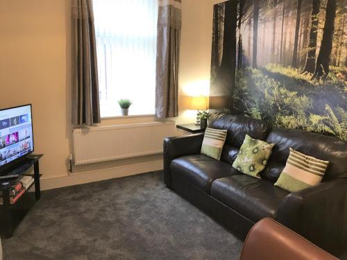a living room with a leather couch and a television at Welcoming spacious 2-bedroom house in St Helens in Saint Helens