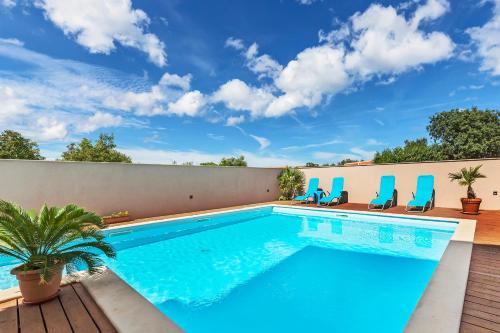 a swimming pool with blue chairs and a fence at Vila Bicikleta Istra in Peroj