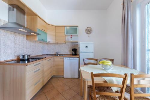 a kitchen with a table and a white refrigerator at Vila Bicikleta Istra in Peroj