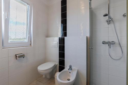 a white bathroom with a toilet and a shower at Vila Bicikleta Istra in Peroj