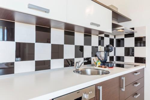 a kitchen with a sink and a black and white checkered wall at Vila Bicikleta Istra in Peroj