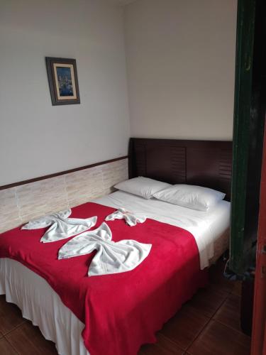 a bedroom with a bed with red blanket and white pillows at Pousada Horto dos Contos in Ouro Preto