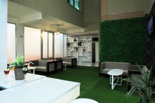 un vestíbulo con sofás, mesas y una pared verde en Riverland Hotel, en Bahir Dar