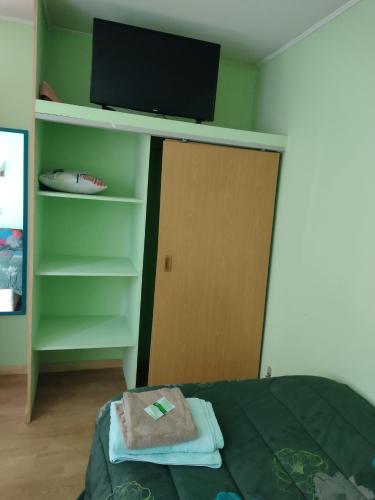 a bedroom with a bed with a tv and a book shelf at Hostal El Toque de Pilar in Punta Arenas
