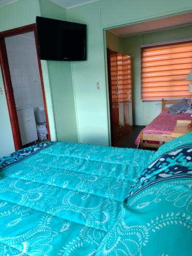 a bedroom with a bed with a blue comforter at Hostal El Toque de Pilar in Punta Arenas