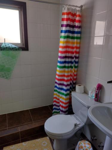 a bathroom with a toilet and a rainbow shower curtain at Hostal El Toque de Pilar in Punta Arenas