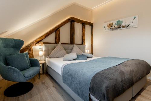 a bedroom with a bed and a blue chair at Hotel auszeit Neunkirchen-Seelscheid in Neunkirchen