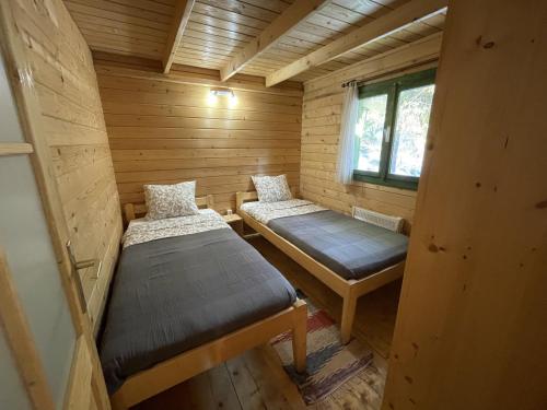 Habitación pequeña con 2 camas en una cabaña de madera en Fenyőtoboz kulcsosház, en Izvoare