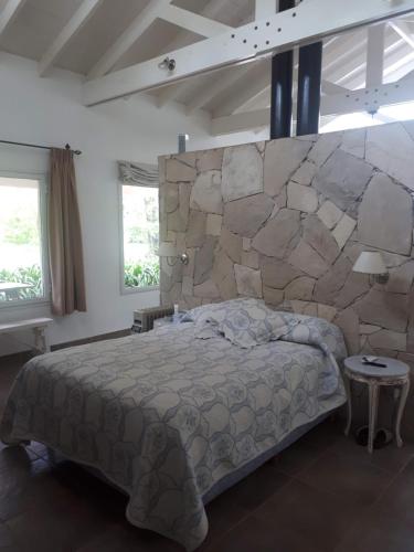 a bedroom with a bed and a stone wall at Preciosa casa loft ideal parejas en Barrio Privado in Balneario Mar Chiquita
