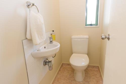 a white bathroom with a toilet and a sink at Hamilton Settlers Motor lodge in Hamilton