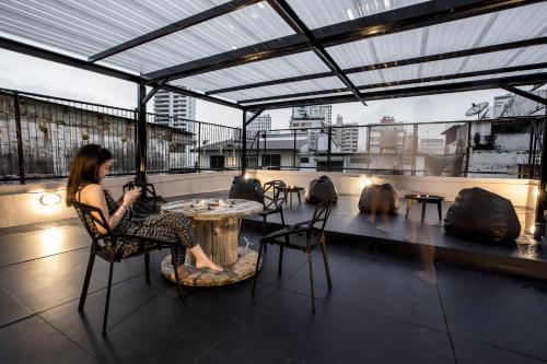 a woman sitting in a chair at a table on a roof at The Blocks Hostel Sukhumvit 10 in Bangkok