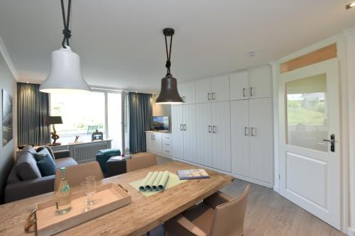 eine Küche und ein Wohnzimmer mit einem großen Holztisch in der Unterkunft Ferienwohnung Eydum Nr 10 in Westerland