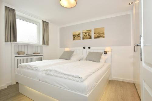 ein weißes Schlafzimmer mit einem großen weißen Bett in der Unterkunft Ferienwohnung Eydum Nr 10 in Westerland