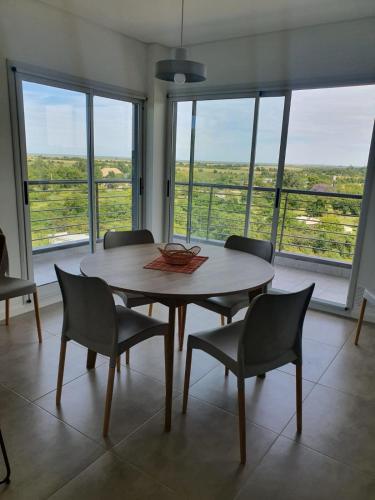 a dining room with a table and chairs and windows at Departamento con vista al río in Victoria
